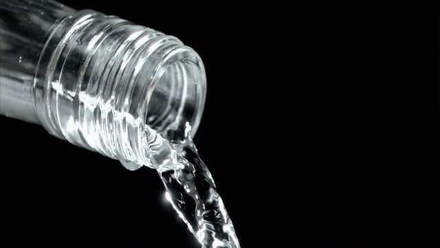 Trickle of water in a super slow motion flowing of the glass bottleneck 