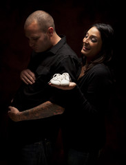 Mixed Race Couple Holding New White Baby Shoes on Black