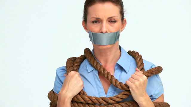 Businesswoman attached with a rope and having tape on her mouth