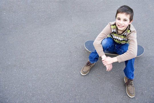 Teenage boy sitting on the skateboard
