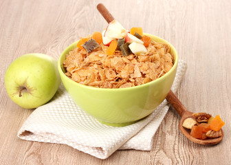 tasty cornflakes in bowl with dried fruits and apple