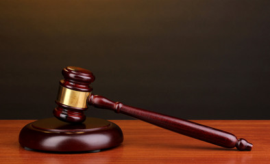 Judge's gavel on wooden table on brown background