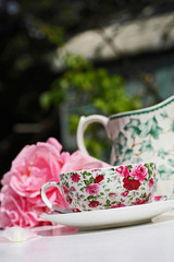Pink roses and an elegant teacup in the garden