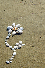 Fototapeta na wymiar Flower made of small stones on sand