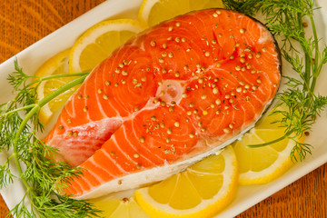 Fresh salmon steak with lemon slice, coriandr and dill.