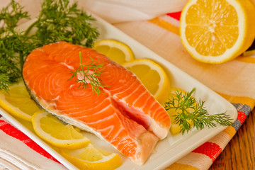 Fresh salmon steak with lemon slice, coriandr and dill