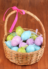 Colorful easter eggs in basket on wooden background