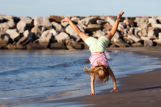 Happy Child Doing Cartwheel By The Ocean