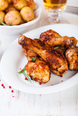 Roast chicken legs on a plate; beer and potatoes in background