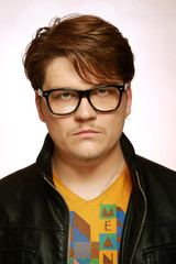 A young man wearing glasses and a leather jacket
