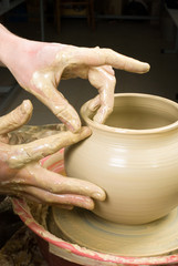 hands of a potter, creating an earthen jar of white clay