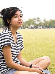 Fototapeta premium A young girl with headphones outdoors. Listening music