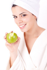 Beautiful young woman in a white spa bath robe eating a apple