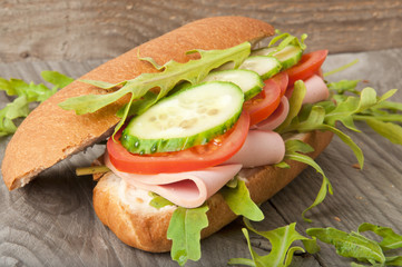 Sandwich with ham, tomato, cucumber and arugula