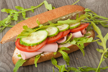 Sandwich with ham, tomato, cucumber and arugula
