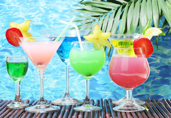 Glasses of cocktails on table on blue sea background