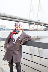 Obraz premium Happy young female with scarf standing on embankment