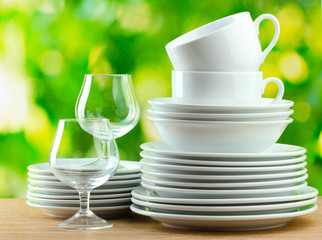 Clean dishes on wooden table on green background