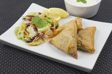 Samosas served with mint raita salad and lemon slices