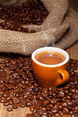 Coffe cup surrounded by toasted beans