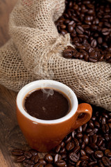 Coffe cup surrounded by toasted beans
