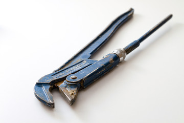 Old plumbers pipe wrench on white