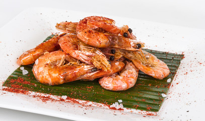 fried black tiger prawns with herbs and spices on banana leaf