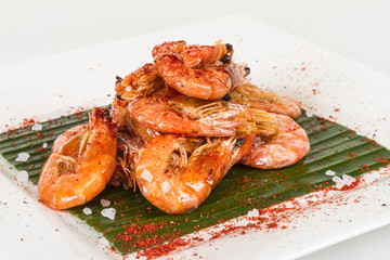 fried black tiger prawns with herbs and spices on banana leaf