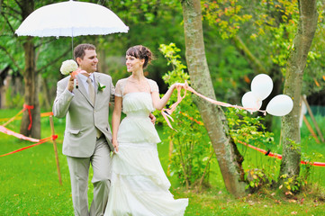 Happy bride and groom walking together in a park