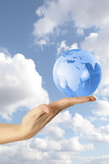 Globe in human hand against blue sky