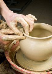 hands of a potter, creating an earthen jar of white clay