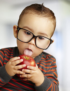 portrait of a handsome kid wearing glasses sucking a red apple i
