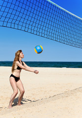 Attractive woman plays in beach volleyball