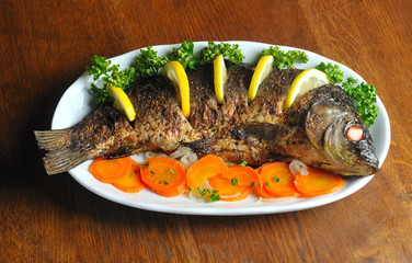 Carp baked with vegetables (carrot, onion, lemon, spice)