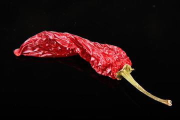 Withered red chili pepper on a black background