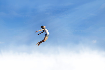 Freedom: Woman jumping over the clouds