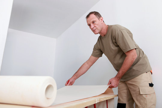 Man decorating apartment with new wallpaper