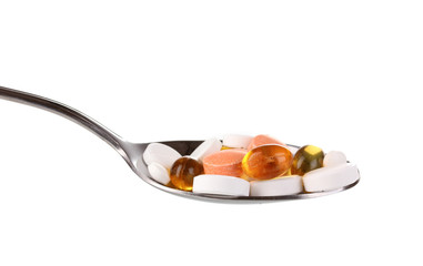 Spoon with pills isolated on white