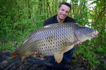 p&ecirc;cheur heureux tenant une grosse carpe commune