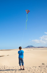 little boy flies a kite in dunes of Corralejo, Fuerteventura