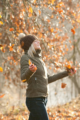 junge frau wirft herbstlaub im gegenlicht