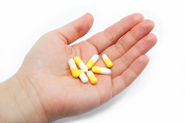 Pharmaceutical capsules in female hand on a white background.