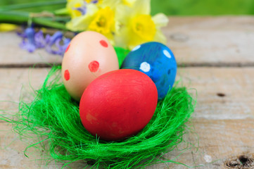 Fototapeta na wymiar Three colorful easter eggs in green nest