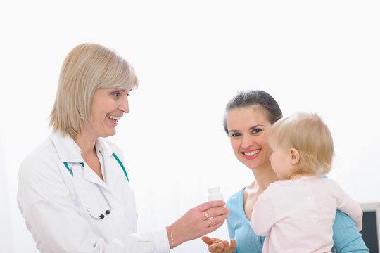 Pediatric doctor giving pills bottle to mother with baby