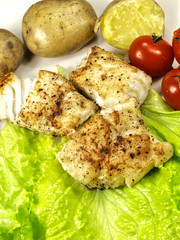 Fried white fish on a plate, vegetables