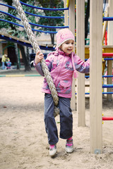 Little girl plays with gym rope at the playground