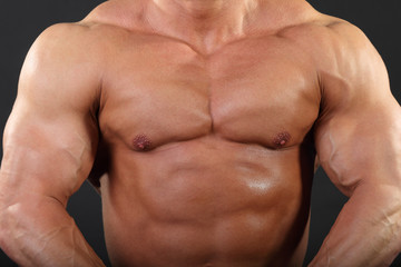 Fototapeta na wymiar Strong chest and hand muscles of undressed tanned bodybuilder