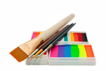 Fototapeta premium face-paints rainbow cakes and brushes over white background