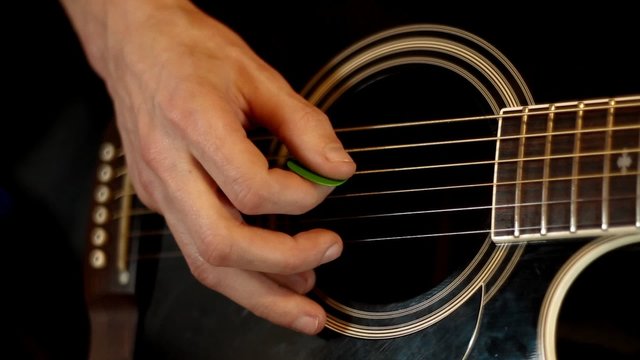 Male hands play on acoustic guitar