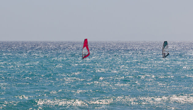 Two windsurfers on a highlighted windy sea